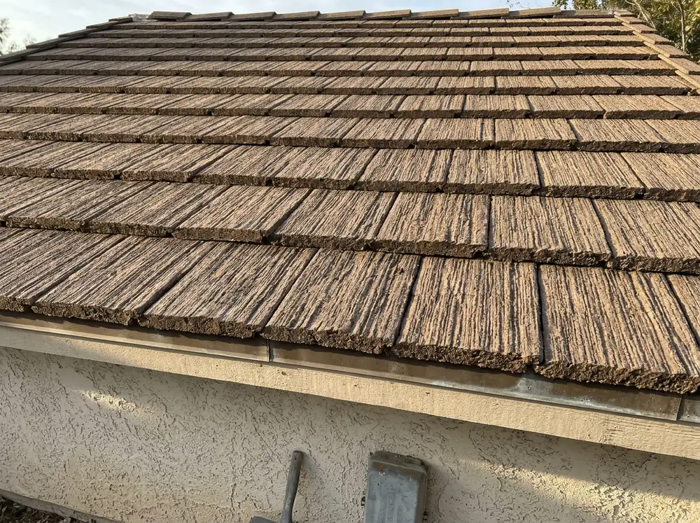 Brown shake-look flat concrete tile roof with a raked, wood-grain texture on each tile, seen at a low angle in afternoon light