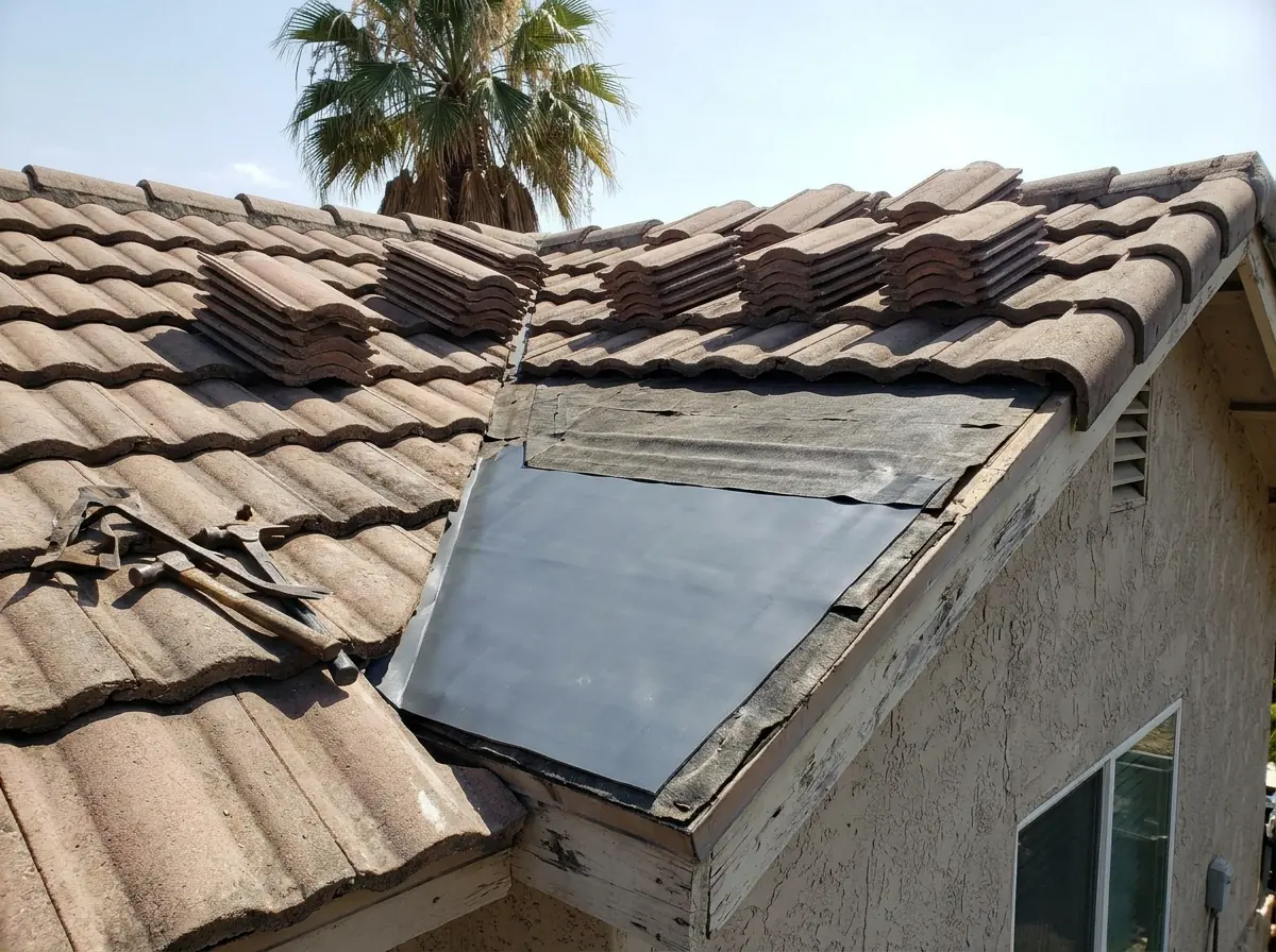 Several tiles lifted on one slope to expose a small patch of new self-adhered underlayment over older black felt